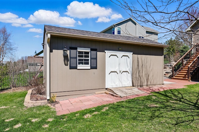view of outbuilding with stairway, fence, and an outbuilding