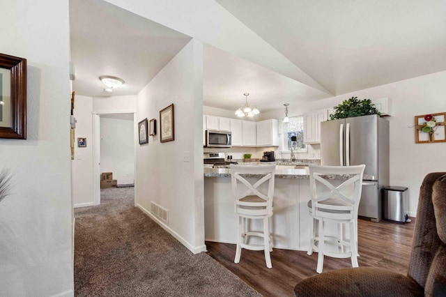 kitchen featuring a kitchen breakfast bar, stainless steel appliances, white cabinets, light stone countertops, and visible vents