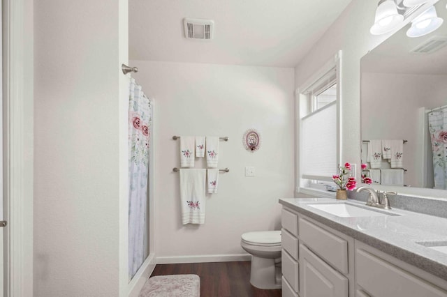 bathroom with wood finished floors, visible vents, a sink, and double vanity