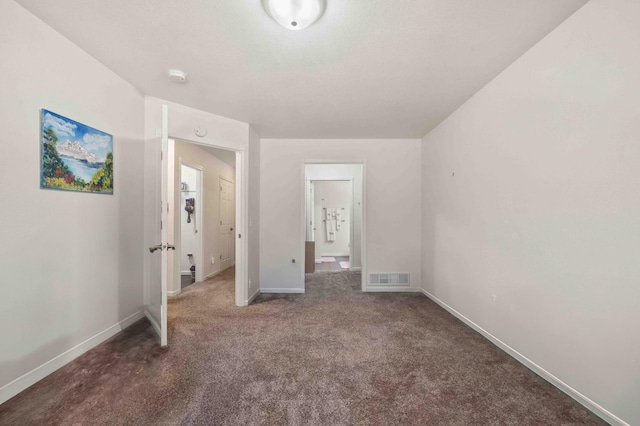 unfurnished bedroom featuring baseboards, carpet flooring, ensuite bathroom, and visible vents