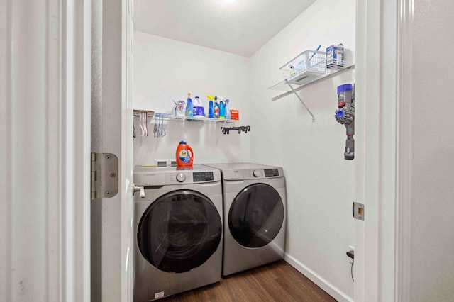 clothes washing area featuring dark wood finished floors, independent washer and dryer, baseboards, and laundry area