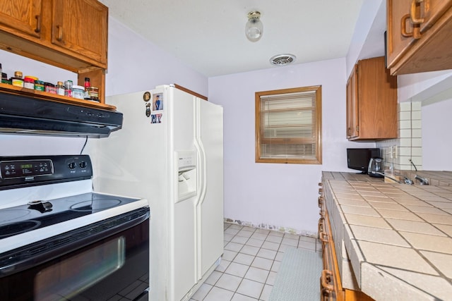 kitchen featuring tile countertops, visible vents, brown cabinets, electric stove, and under cabinet range hood