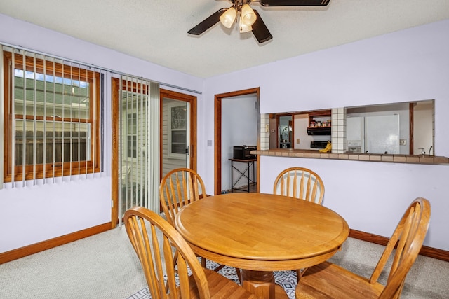 dining area featuring carpet floors, baseboards, bar area, and ceiling fan