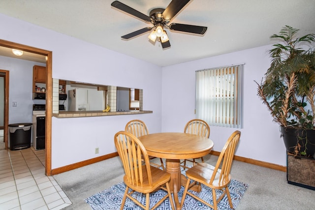 dining space featuring baseboards, a ceiling fan, and light colored carpet