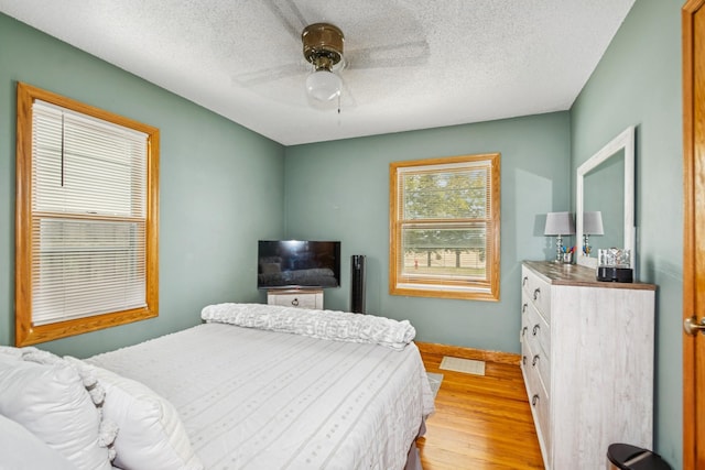 bedroom with baseboards, a textured ceiling, ceiling fan, and light wood finished floors