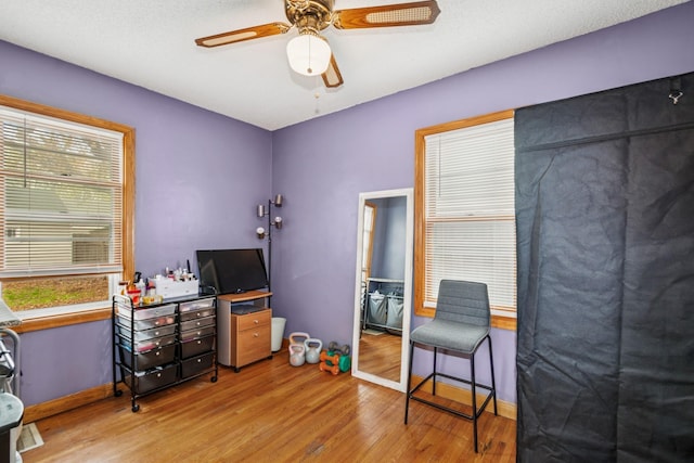 interior space with baseboards, a ceiling fan, and wood finished floors