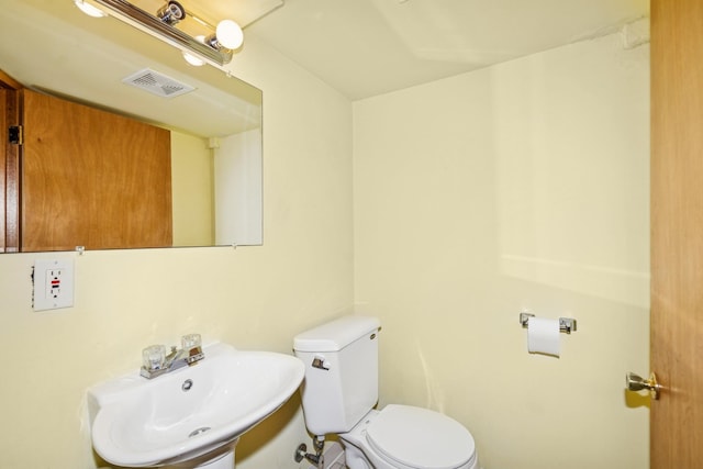 half bathroom with toilet, visible vents, and a sink