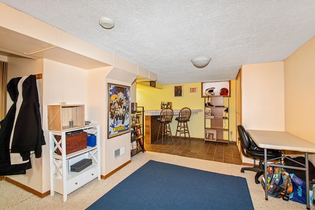 carpeted home office with baseboards, indoor bar, a textured ceiling, and visible vents