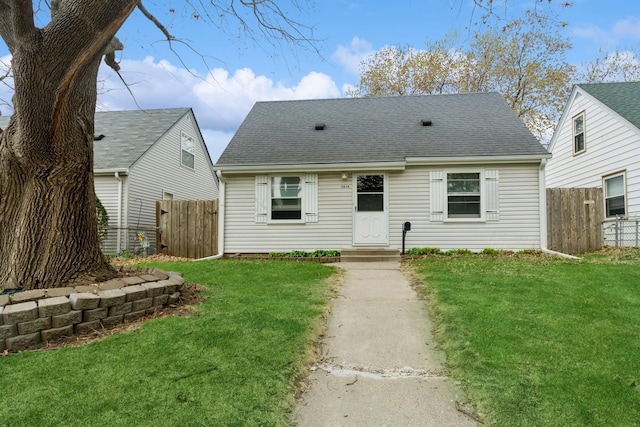 exterior space with fence, a shingled roof, and a yard
