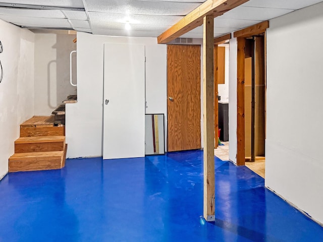 finished basement with stairs, a paneled ceiling, and visible vents