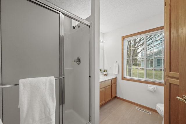 8569 Telford Ln N, Brooklyn Park, MN 55443 - full bathroom featuring a shower stall, vanity, a textured ceiling, baseboards, and toilet