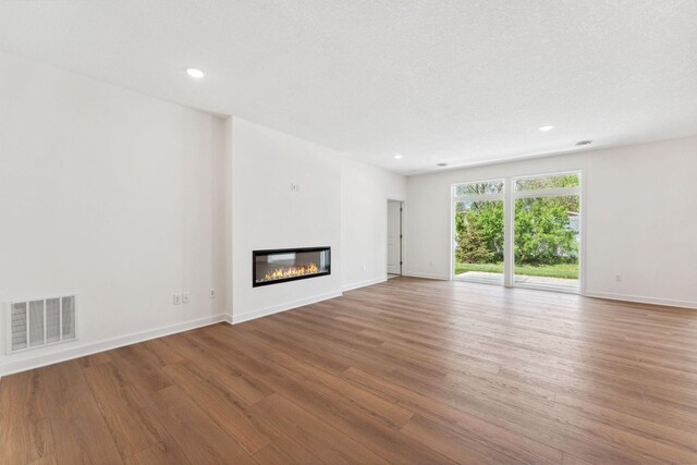 17729 Everest Ave, Lakeville, MN 55044 - unfurnished living room featuring wood finished floors, a glass covered fireplace, baseboards, and recessed lighting