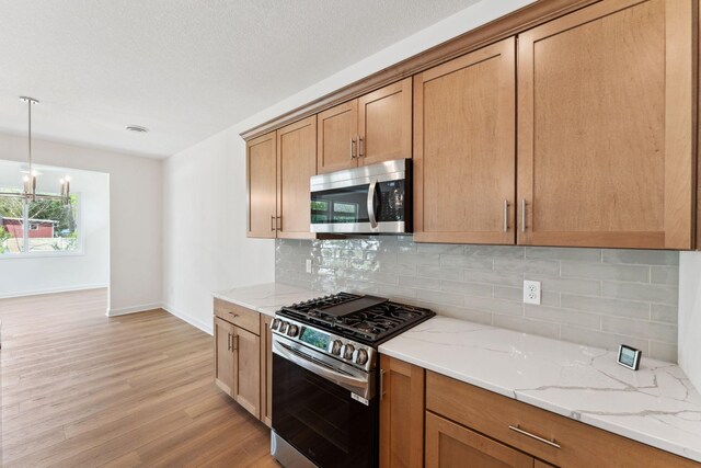 17729 Everest Ave, Lakeville, MN 55044 - kitchen with appliances with stainless steel finishes, light wood finished floors, tasteful backsplash, baseboards, and light stone counters