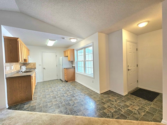 1065 Blackbird Trl SW Unit 8, Hutchinson, MN 55350 - kitchen with freestanding refrigerator, lofted ceiling, stone finish floors, backsplash, and baseboards