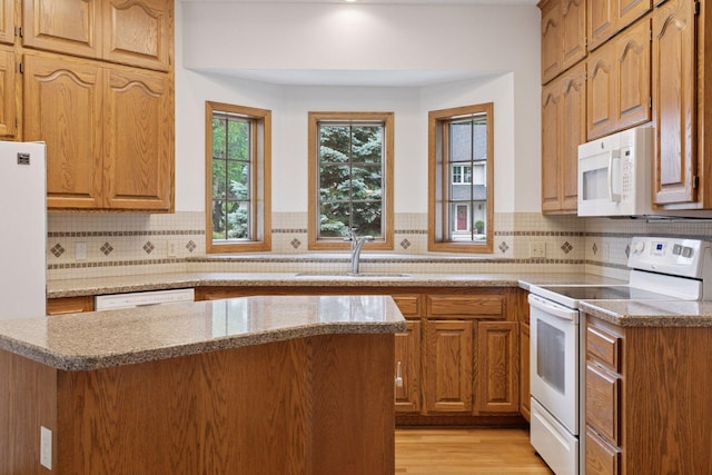 11765 177th St W, Lakeville, MN 55044 - kitchen featuring white appliances, light stone counters, tasteful backsplash, light wood-type flooring, and brown cabinetry