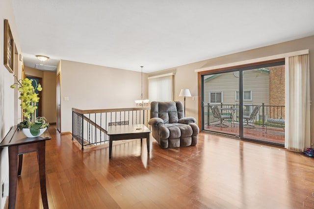 living area with visible vents, wood finished floors, a chandelier, and an upstairs landing