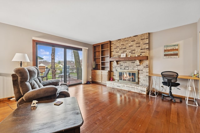 living room with a fireplace, built in features, radiator, baseboards, and wood finished floors