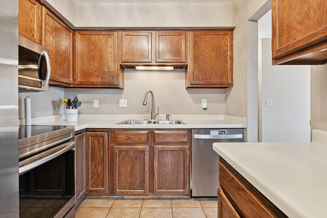 kitchen featuring a sink, light countertops, light tile patterned floors, and stainless steel appliances