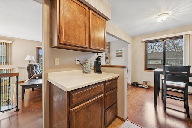 kitchen with brown cabinetry, light countertops, light wood-style flooring, and baseboards