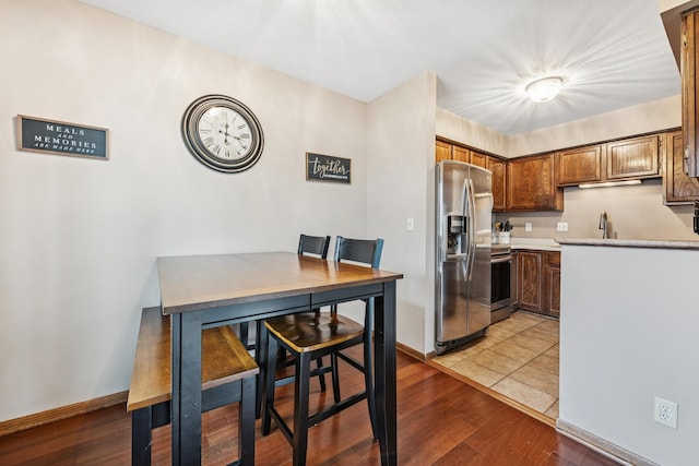 kitchen with baseboards, light countertops, wood finished floors, and stainless steel appliances