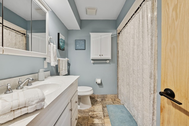 full bath with vanity, visible vents, toilet, baseboards, and stone finish floor
