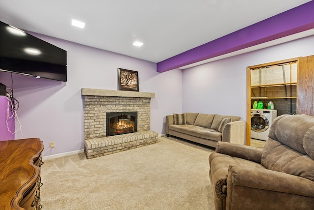 living room featuring a brick fireplace, baseboards, washer / dryer, and carpet