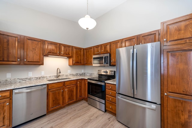 130 Teton Ln Unit 8, Mankato, MN 56001 - kitchen featuring appliances with stainless steel finishes, light wood-style flooring, light stone countertops, brown cabinetry, and a towering ceiling