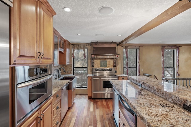 1801 Elliot Ave Unit 4And 6, Minneapolis, MN 55404 - kitchen featuring appliances with stainless steel finishes, a sink, wall chimney exhaust hood, light stone countertops, and a textured ceiling