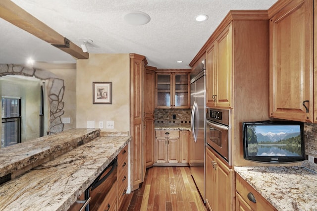 1801 Elliot Ave Unit 4And 6, Minneapolis, MN 55404 - kitchen featuring appliances with stainless steel finishes, tasteful backsplash, light stone counters, light wood-style floors, and a textured ceiling