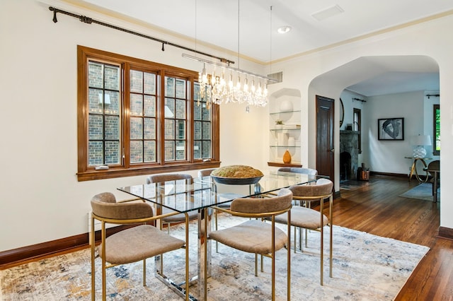 dining space featuring arched walkways, baseboards, dark wood-style flooring, built in features, and crown molding