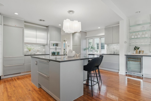 kitchen featuring beverage cooler, dark countertops, modern cabinets, gray cabinetry, and decorative backsplash