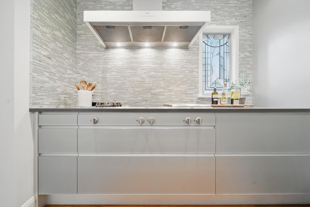 bar with wall chimney range hood, tasteful backsplash, and cooktop