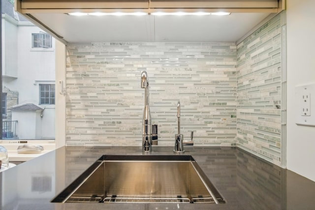 kitchen featuring a sink, backsplash, and dark countertops