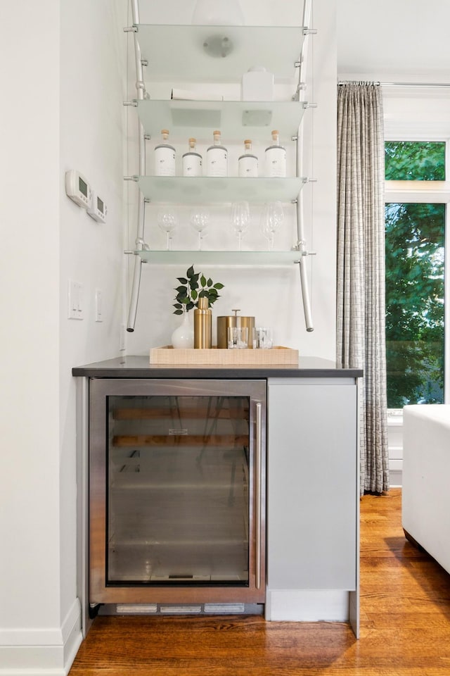 indoor dry bar with wine cooler, wood finished floors, and plenty of natural light