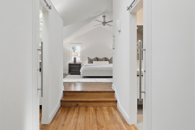 bedroom featuring light wood finished floors, baseboards, lofted ceiling, and ceiling fan