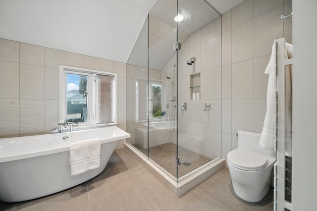 full bathroom featuring tile walls, a stall shower, a freestanding tub, lofted ceiling, and plenty of natural light