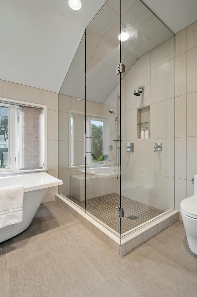 full bathroom with a stall shower, tile walls, toilet, a soaking tub, and vaulted ceiling