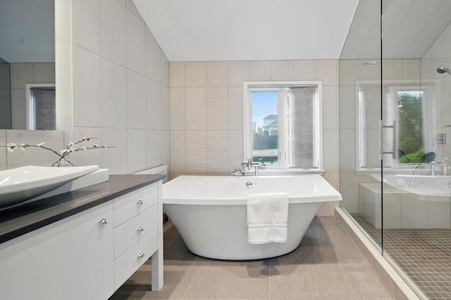 full bathroom featuring tile walls, plenty of natural light, a shower stall, vanity, and a soaking tub