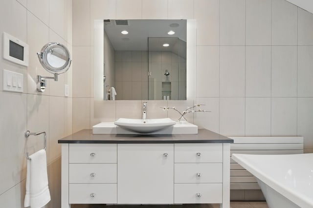 bathroom with tile walls, vanity, tiled shower, decorative backsplash, and a soaking tub