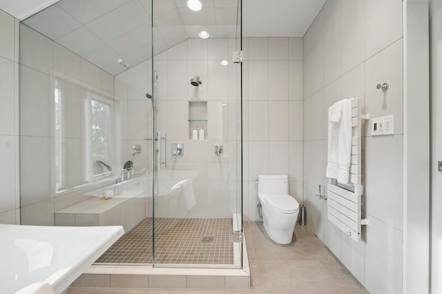 full bathroom featuring tile walls, a stall shower, toilet, and tile patterned flooring
