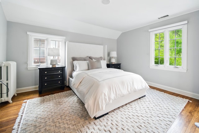 bedroom featuring radiator heating unit, baseboards, wood finished floors, crown molding, and vaulted ceiling