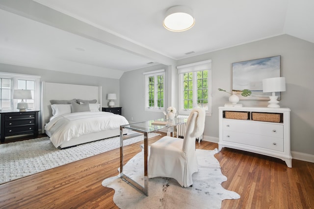 bedroom with vaulted ceiling, wood finished floors, and baseboards