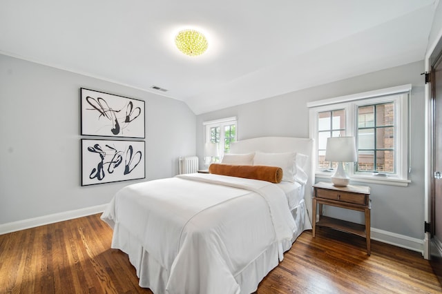 bedroom with radiator, baseboards, wood finished floors, and vaulted ceiling