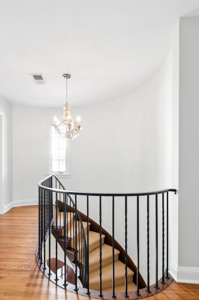 stairway featuring baseboards, wood finished floors, and a chandelier