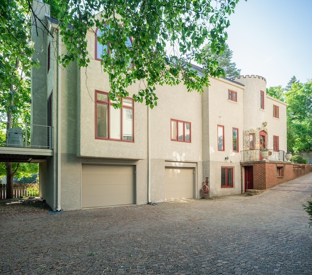 view of front facade with a garage, stucco siding, and decorative driveway