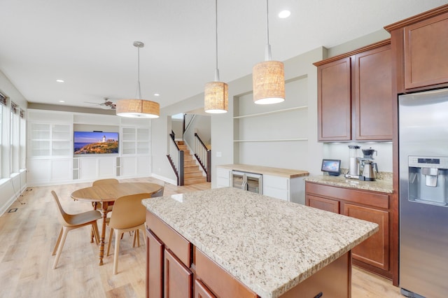 20024 Fern Glen Ln N, Forest Lake, MN 55025 - kitchen with stainless steel fridge with ice dispenser, light wood finished floors, a kitchen island, hanging light fixtures, and light stone counters