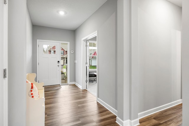 entryway featuring baseboards and dark wood-style floors