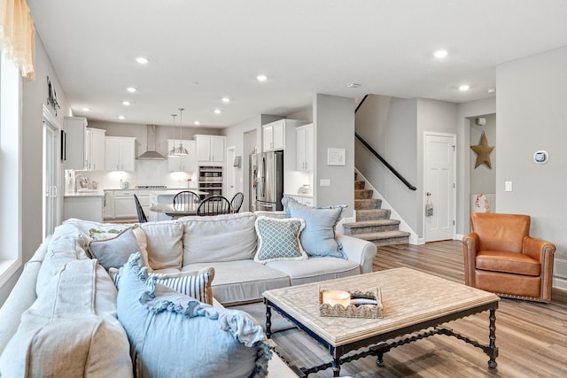 living area with light wood-type flooring, recessed lighting, stairs, and baseboards