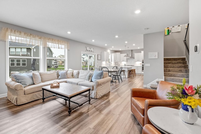 living area with recessed lighting, baseboards, stairway, and light wood-type flooring