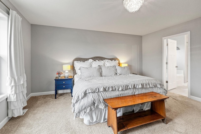 carpeted bedroom featuring baseboards and ensuite bath